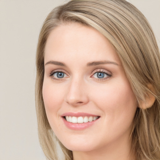 Joyful white young-adult female with long  brown hair and blue eyes