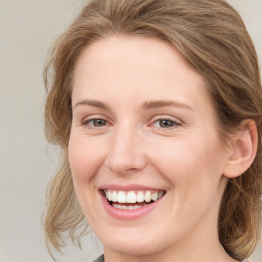 Joyful white young-adult female with medium  brown hair and green eyes