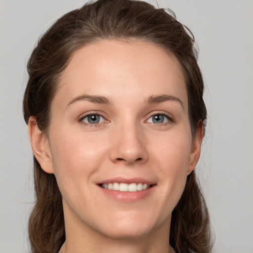 Joyful white young-adult female with medium  brown hair and grey eyes