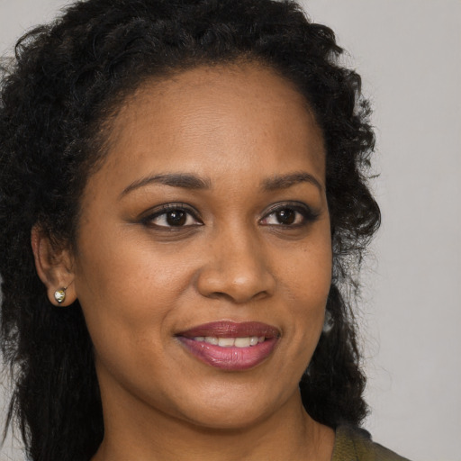 Joyful black young-adult female with long  brown hair and brown eyes