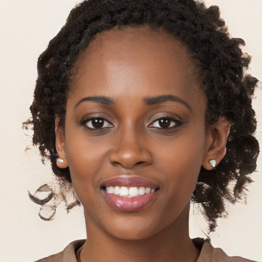 Joyful black young-adult female with long  brown hair and brown eyes