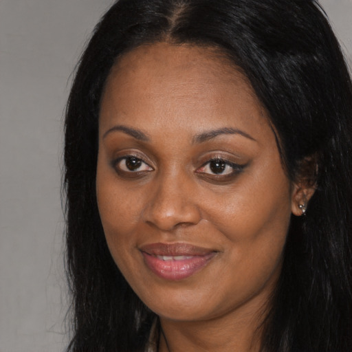 Joyful black young-adult female with long  brown hair and brown eyes
