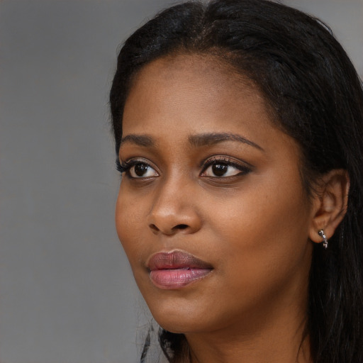 Joyful black young-adult female with long  black hair and brown eyes