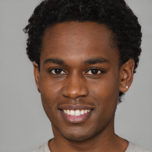 Joyful black young-adult male with short  brown hair and brown eyes