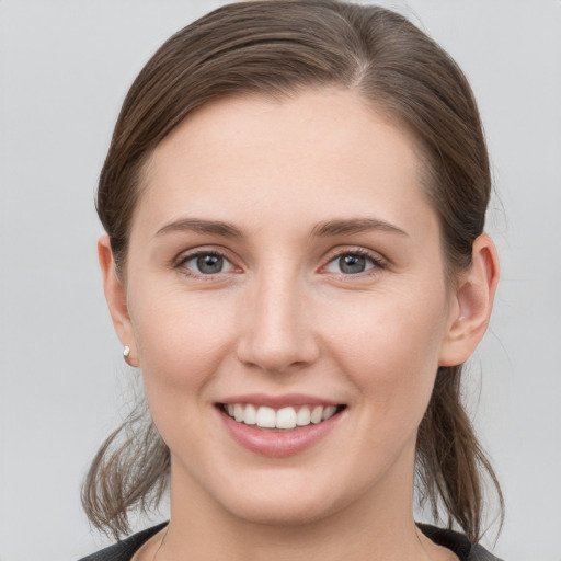 Joyful white young-adult female with medium  brown hair and grey eyes