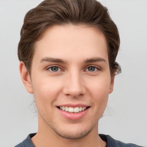 Joyful white young-adult male with short  brown hair and grey eyes