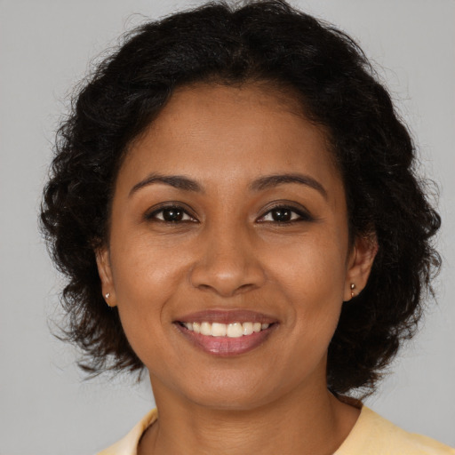 Joyful black young-adult female with long  brown hair and brown eyes