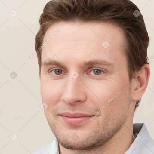 Joyful white young-adult male with short  brown hair and grey eyes