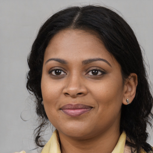 Joyful black young-adult female with long  brown hair and brown eyes