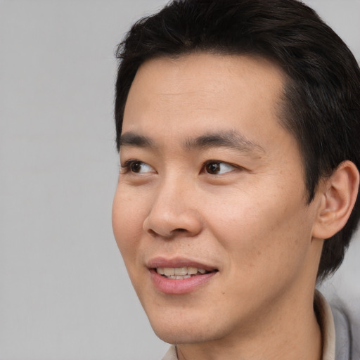 Joyful asian young-adult male with short  brown hair and brown eyes