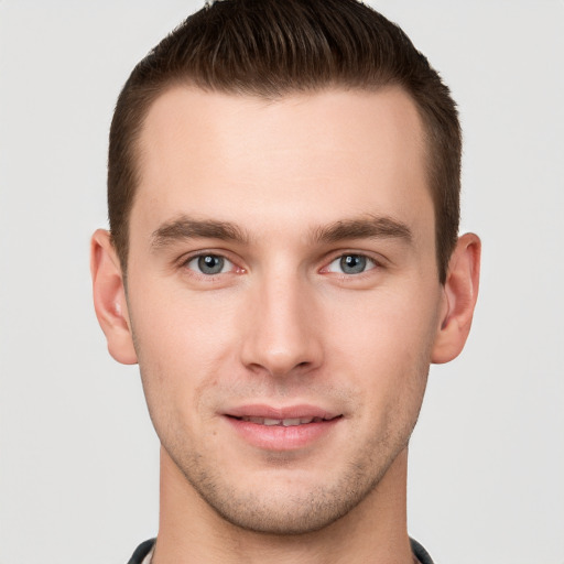 Joyful white young-adult male with short  brown hair and grey eyes