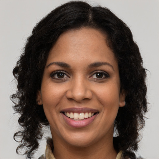Joyful black young-adult female with long  brown hair and brown eyes