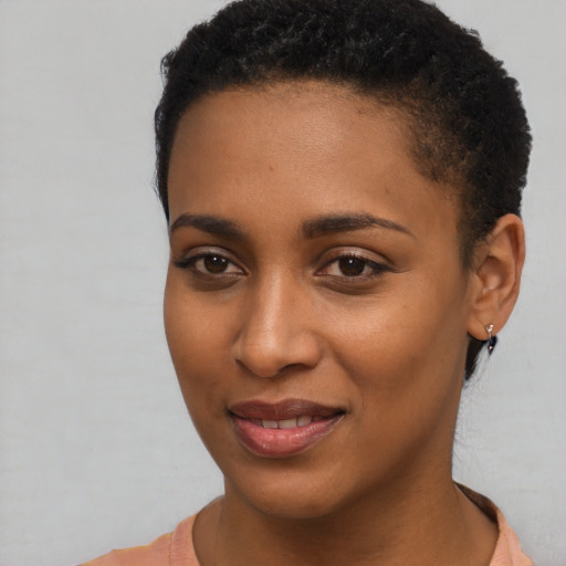 Joyful black young-adult female with short  black hair and brown eyes