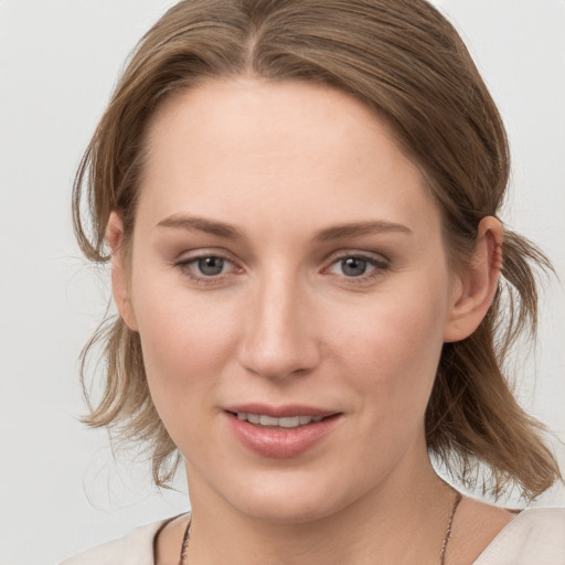 Joyful white young-adult female with medium  brown hair and blue eyes