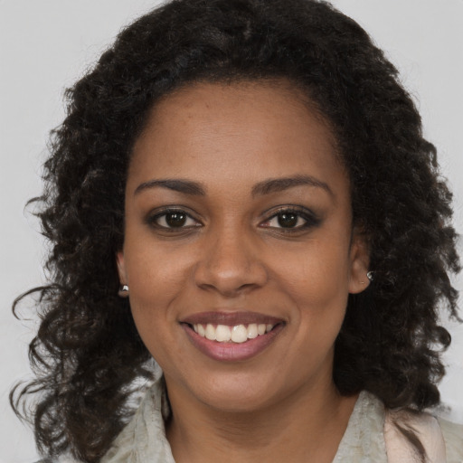 Joyful black young-adult female with long  brown hair and brown eyes