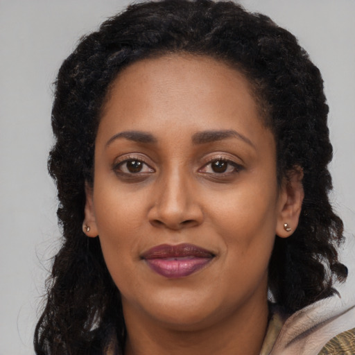 Joyful black adult female with long  brown hair and brown eyes