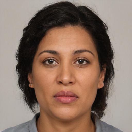 Joyful latino adult female with medium  brown hair and brown eyes