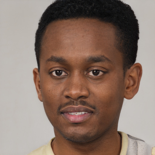 Joyful black young-adult male with short  black hair and brown eyes