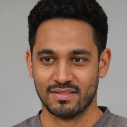 Joyful latino young-adult male with short  black hair and brown eyes