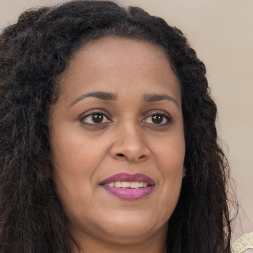 Joyful black young-adult female with long  brown hair and brown eyes