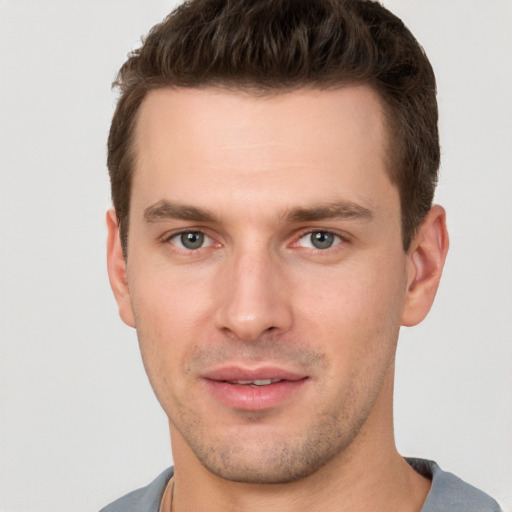 Joyful white young-adult male with short  brown hair and grey eyes