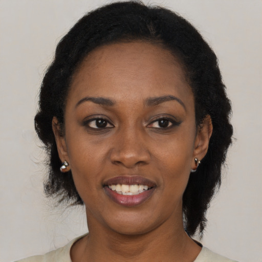 Joyful black young-adult female with long  brown hair and brown eyes