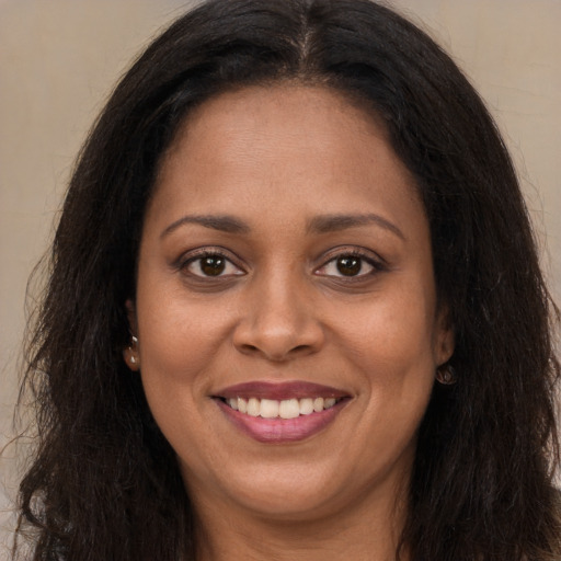 Joyful black young-adult female with long  brown hair and brown eyes