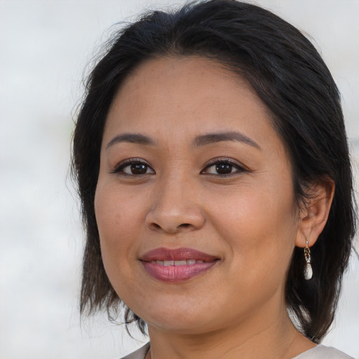 Joyful latino adult female with medium  brown hair and brown eyes