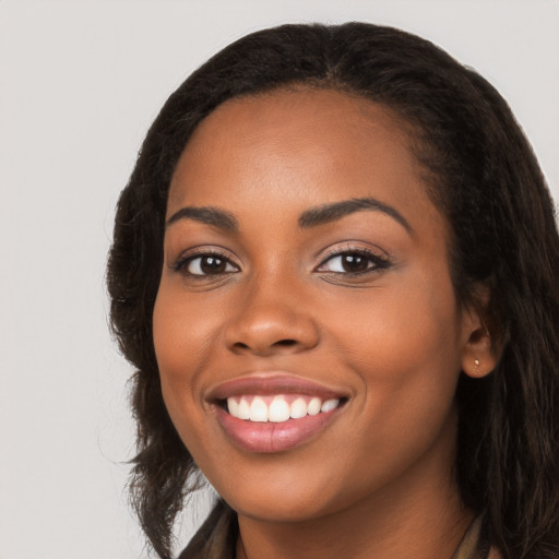 Joyful black young-adult female with long  black hair and brown eyes