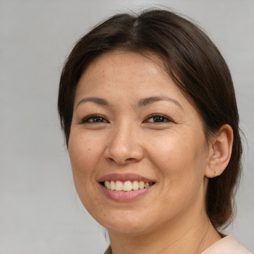 Joyful asian adult female with medium  brown hair and brown eyes