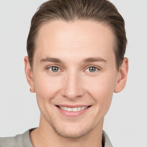 Joyful white young-adult male with short  brown hair and grey eyes