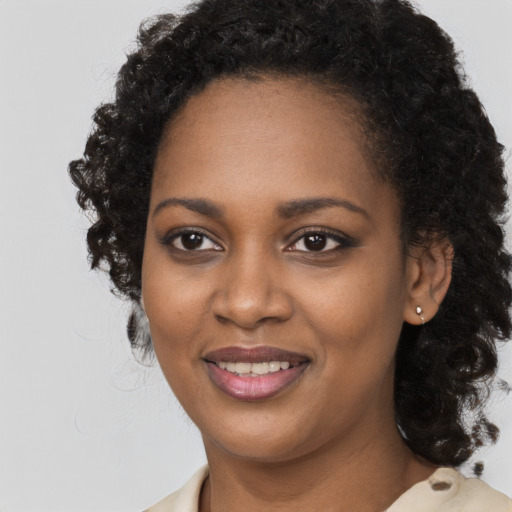 Joyful black young-adult female with long  black hair and brown eyes