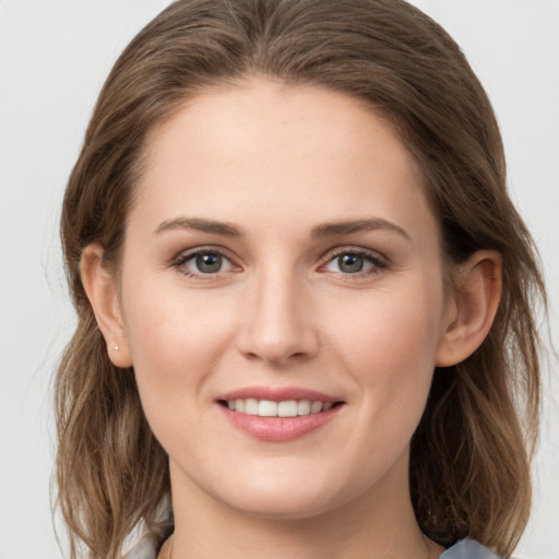 Joyful white young-adult female with medium  brown hair and grey eyes