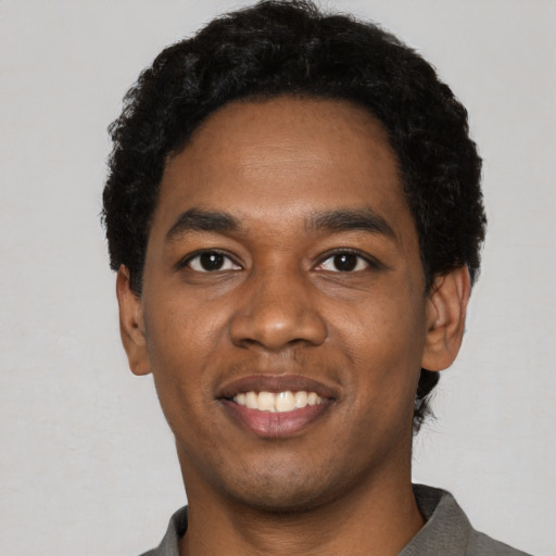 Joyful black young-adult male with short  black hair and brown eyes