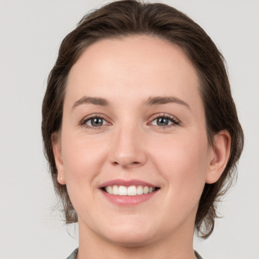 Joyful white young-adult female with medium  brown hair and grey eyes