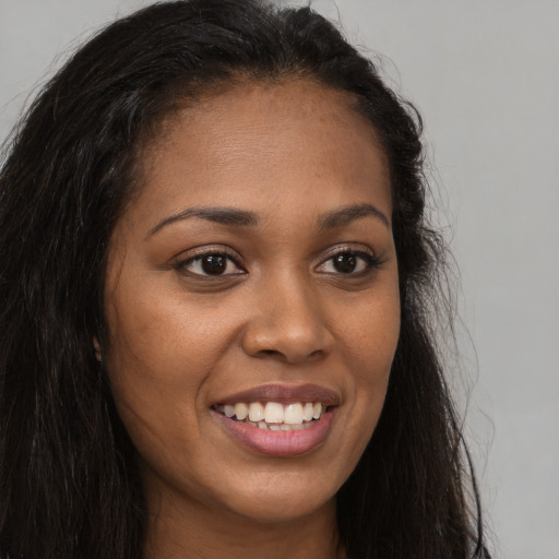 Joyful black young-adult female with long  brown hair and brown eyes