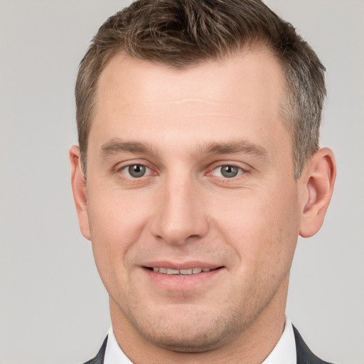 Joyful white young-adult male with short  brown hair and grey eyes