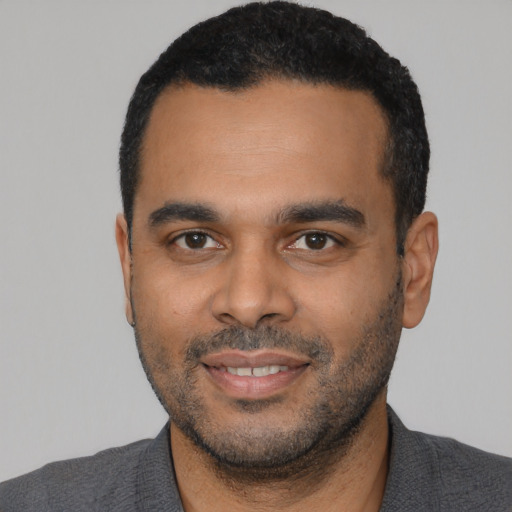 Joyful black young-adult male with short  black hair and brown eyes