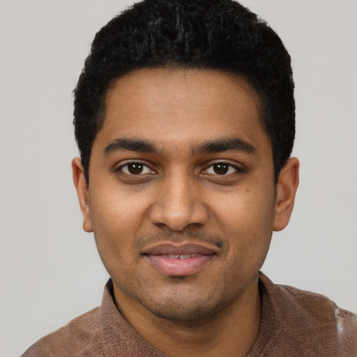 Joyful black young-adult male with short  black hair and brown eyes