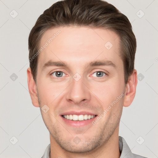 Joyful white young-adult male with short  brown hair and grey eyes