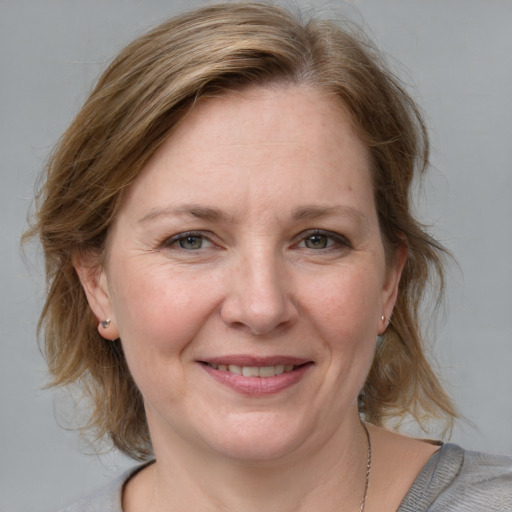 Joyful white adult female with medium  brown hair and blue eyes