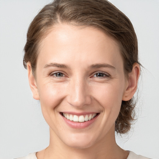 Joyful white young-adult female with medium  brown hair and grey eyes