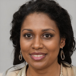 Joyful black young-adult female with long  brown hair and brown eyes