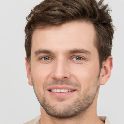 Joyful white young-adult male with short  brown hair and grey eyes