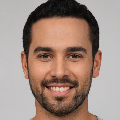 Joyful white young-adult male with short  black hair and brown eyes