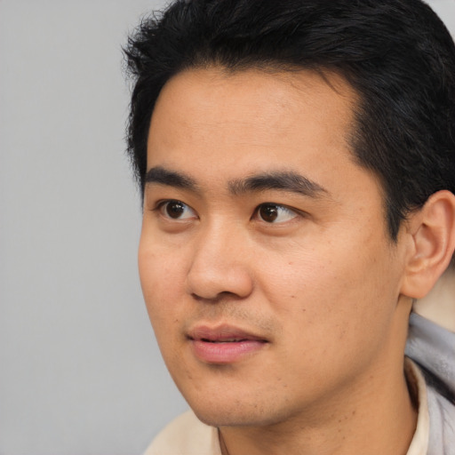 Joyful asian young-adult male with short  black hair and brown eyes