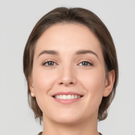 Joyful white young-adult female with medium  brown hair and grey eyes