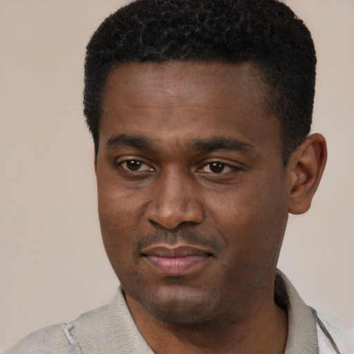 Joyful black young-adult male with short  black hair and brown eyes