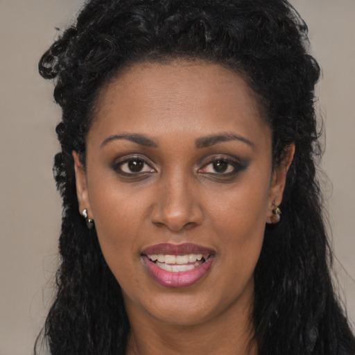 Joyful black young-adult female with long  black hair and brown eyes