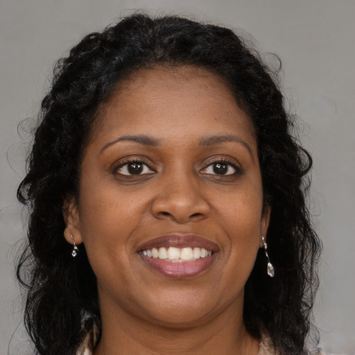 Joyful black young-adult female with long  brown hair and brown eyes